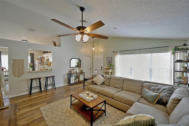 759 Cape Cod Cir, Valrico, FL 33594 - living room with vaulted ceiling, a textured ceiling, a ceiling fan, wood finished floors, and baseboards