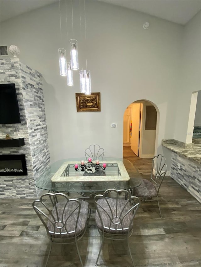 2390 Bentley Dr, Palm Harbor, FL 34684 - dining area with wood finished floors, a towering ceiling, arched walkways, and a fireplace