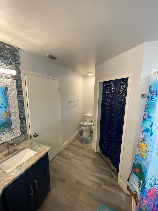 2390 Bentley Dr, Palm Harbor, FL 34684 - full bath with wood finished floors, toilet, vanity, and baseboards