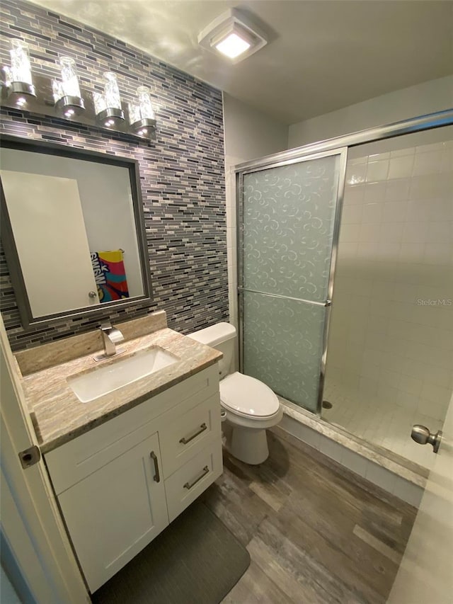 2390 Bentley Dr, Palm Harbor, FL 34684 - bathroom with wood finished floors, tile walls, a stall shower, vanity, and toilet