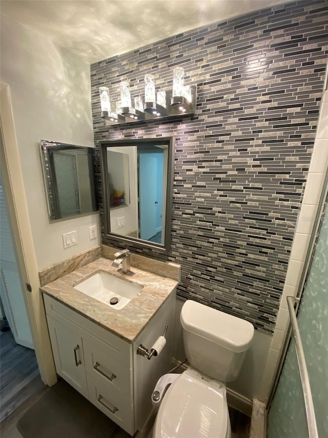 2390 Bentley Dr, Palm Harbor, FL 34684 - bathroom with toilet, vanity, backsplash, an enclosed shower, and tile walls