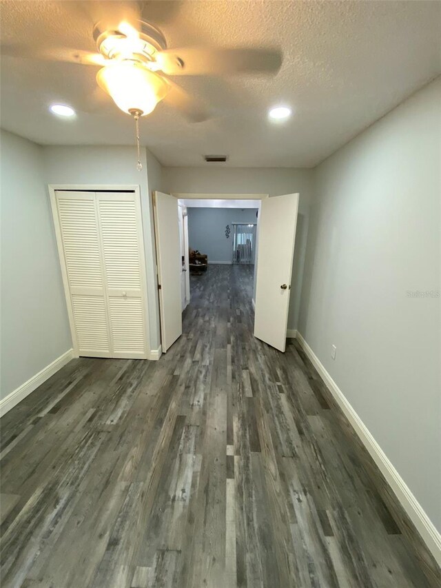 2390 Bentley Dr, Palm Harbor, FL 34684 - unfurnished bedroom with dark wood finished floors, baseboards, a textured ceiling, a closet, and a ceiling fan
