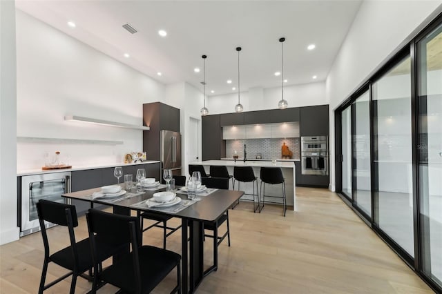 3817 W San Nicholas St, Tampa, FL 33629 - dining space featuring wine cooler, a towering ceiling, light wood-style floors, a dry bar, and recessed lighting