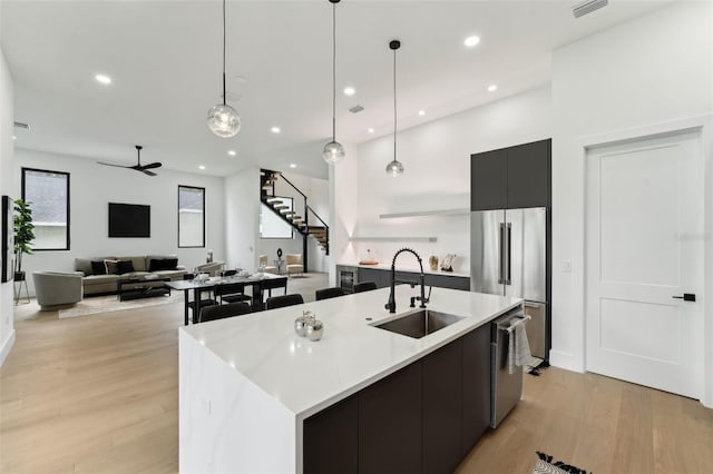 3817 W San Nicholas St, Tampa, FL 33629 - kitchen featuring a sink, appliances with stainless steel finishes, modern cabinets, light wood-style flooring, and a center island with sink