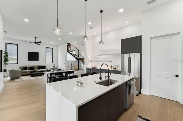 3817 W San Nicholas St, Tampa, FL 33629 - kitchen featuring stainless steel appliances, modern cabinets, light wood-style floors, an island with sink, and hanging light fixtures