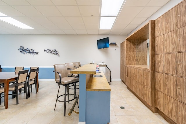 80 Rogers St Unit 6D, Clearwater, FL 33756 - kitchen with a breakfast bar area, light tile patterned floors, a paneled ceiling, wood counters, and baseboards