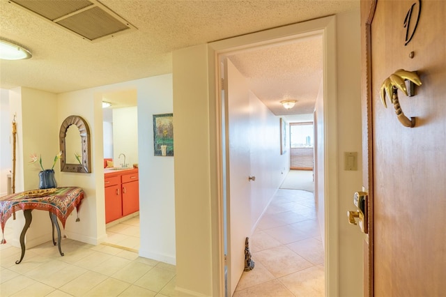 80 Rogers St Unit 6D, Clearwater, FL 33756 - hallway with a textured ceiling, light tile patterned flooring, a sink, and baseboards