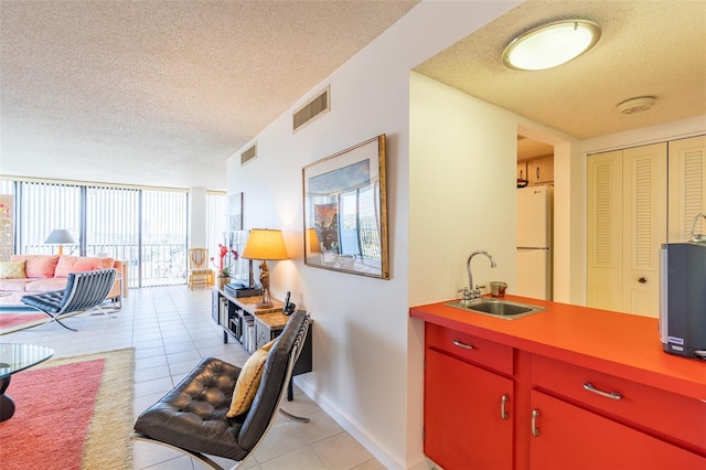 80 Rogers St Unit 6D, Clearwater, FL 33756 - kitchen with a sink, red cabinets, freestanding refrigerator, a textured ceiling, and light tile patterned floors