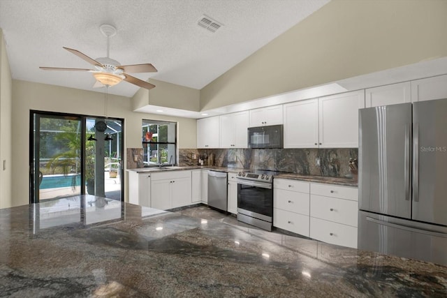 8737 Beaver Ln, Port Richey, FL 34668 - kitchen featuring appliances with stainless steel finishes, tasteful backsplash, white cabinetry, ceiling fan, and lofted ceiling
