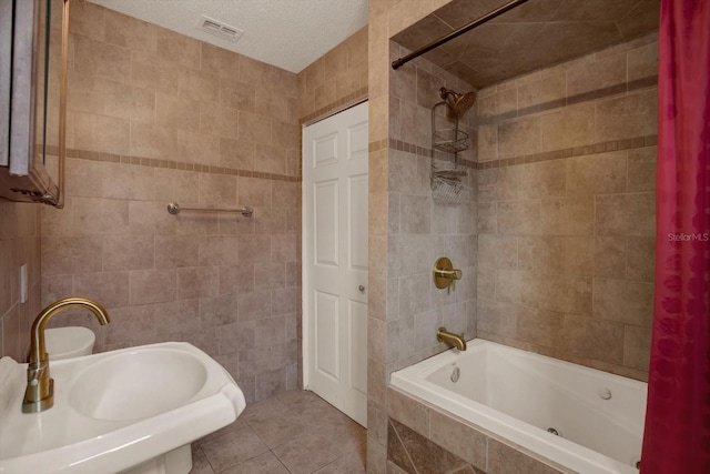 8737 Beaver Ln, Port Richey, FL 34668 - bathroom with tile walls, tiled shower / bath, tile patterned flooring, and a textured ceiling
