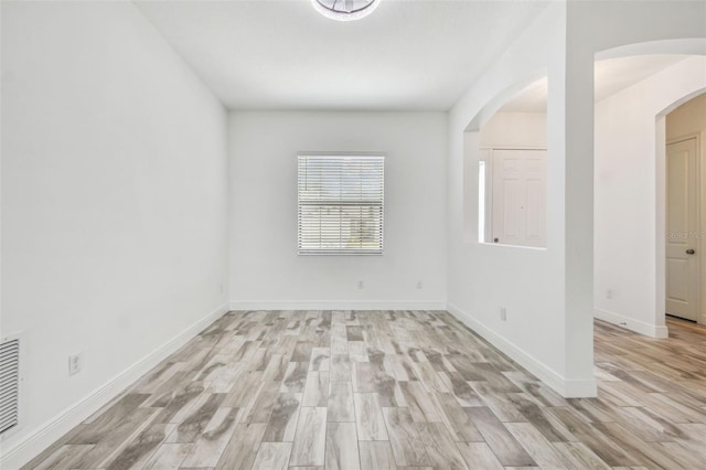 12710 Wheatgrass Ct, Parrish, FL 34219 - empty room with light wood-style floors, arched walkways, and baseboards