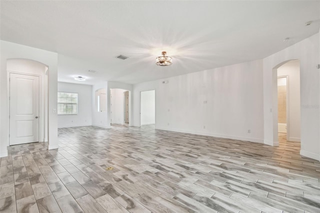12710 Wheatgrass Ct, Parrish, FL 34219 - unfurnished living room with light wood finished floors, arched walkways, and baseboards