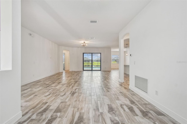 12710 Wheatgrass Ct, Parrish, FL 34219 - spare room with arched walkways, light wood finished floors, and baseboards