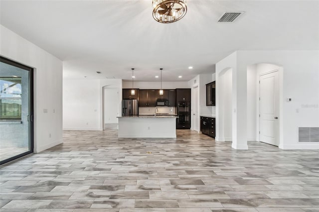 12710 Wheatgrass Ct, Parrish, FL 34219 - unfurnished living room featuring baseboards, recessed lighting, arched walkways, light wood-style floors, and a chandelier
