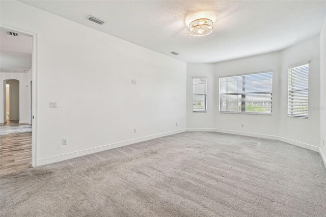12710 Wheatgrass Ct, Parrish, FL 34219 - carpeted empty room with arched walkways, baseboards, and a textured ceiling