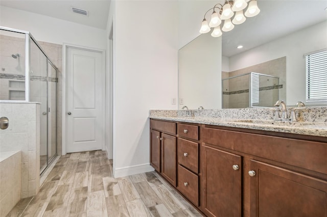 12710 Wheatgrass Ct, Parrish, FL 34219 - full bathroom with a stall shower, double vanity, a chandelier, and wood finished floors