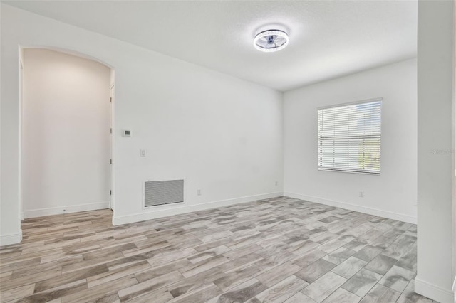 12710 Wheatgrass Ct, Parrish, FL 34219 - spare room featuring arched walkways, light wood-style flooring, and baseboards