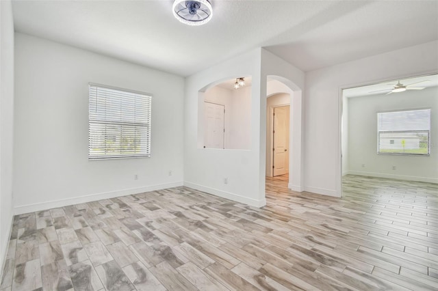 12710 Wheatgrass Ct, Parrish, FL 34219 - empty room featuring healthy amount of natural light, arched walkways, light wood-style floors, and ceiling fan