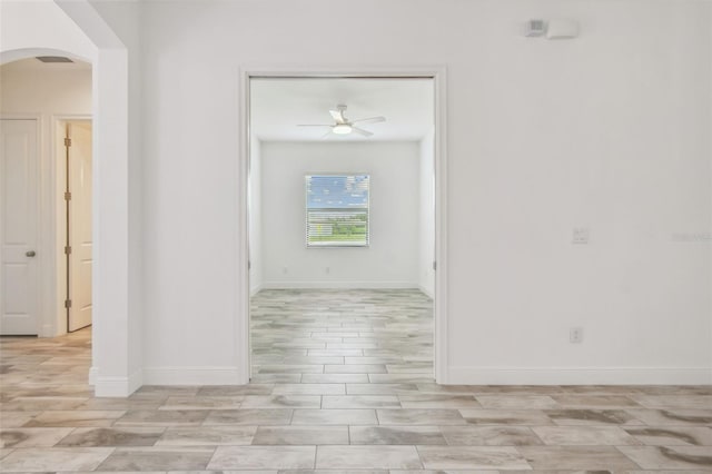 12710 Wheatgrass Ct, Parrish, FL 34219 - empty room featuring arched walkways, a ceiling fan, baseboards, and light wood-type flooring