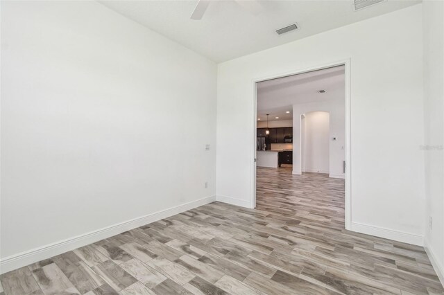 12710 Wheatgrass Ct, Parrish, FL 34219 - empty room featuring ceiling fan, light wood-type flooring, arched walkways, and baseboards