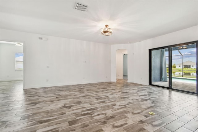 12710 Wheatgrass Ct, Parrish, FL 34219 - spare room featuring arched walkways, wood finished floors, and baseboards