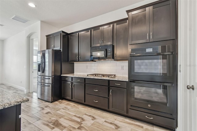 12710 Wheatgrass Ct, Parrish, FL 34219 - kitchen featuring black appliances, decorative backsplash, light stone countertops, and arched walkways