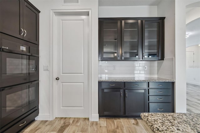 12710 Wheatgrass Ct, Parrish, FL 34219 - bar featuring arched walkways, tasteful backsplash, light wood-style floors, and baseboards