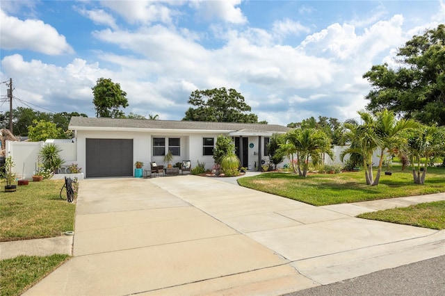 ranch-style home featuring an attached garage, concrete driveway, stucco siding, and a front lawn