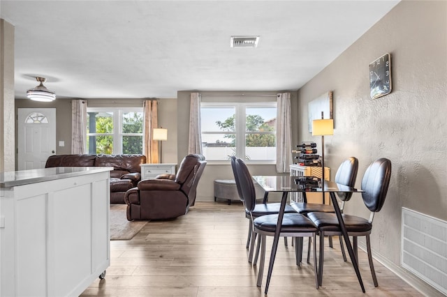 dining area featuring healthy amount of natural light, a textured wall, and light wood-style floors