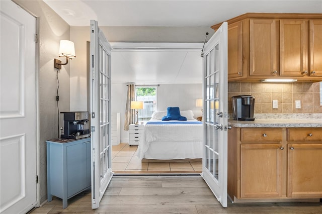 kitchen with french doors, light wood-style floors, tasteful backsplash, and brown cabinetry