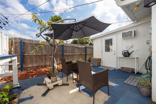 view of patio with a wall mounted air conditioner, fence, and outdoor dining area