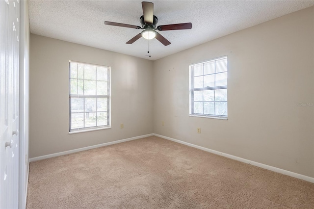 carpeted spare room with a ceiling fan, baseboards, and a textured ceiling