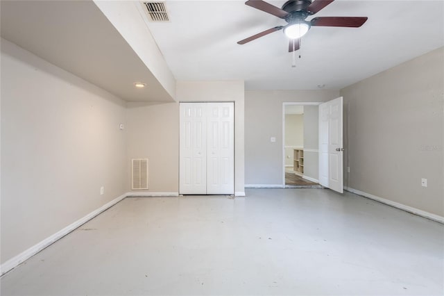 unfurnished bedroom with concrete flooring, baseboards, a ceiling fan, and a closet