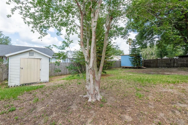 fenced backyard featuring a storage shed and an outbuilding