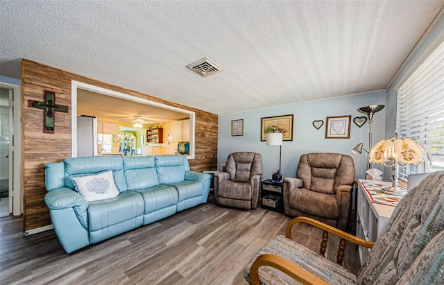 6111 2nd Ave, New Port Richey, FL 34653 - living room with wooden walls, a textured ceiling, wood finished floors, plenty of natural light, and ceiling fan