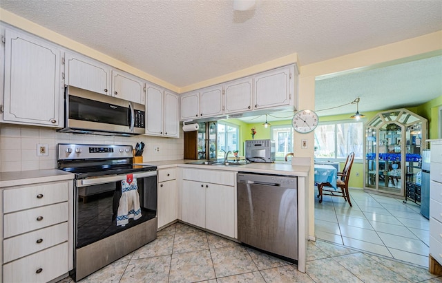 6111 2nd Ave, New Port Richey, FL 34653 - kitchen featuring appliances with stainless steel finishes, a sink, light countertops, a textured ceiling, and backsplash