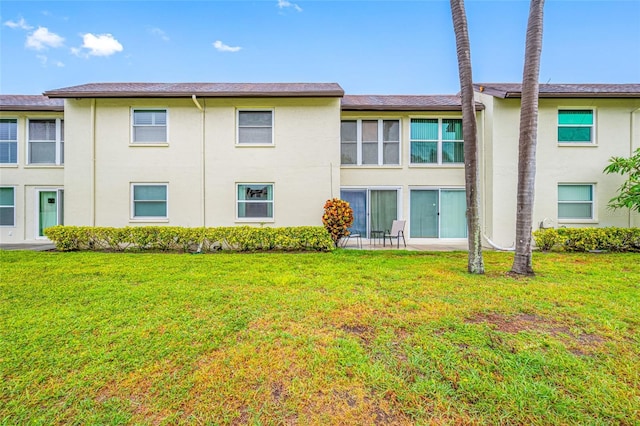 1100 E Bay Dr Unit 60, Largo, FL 33770 - rear view of house featuring stucco siding and a lawn