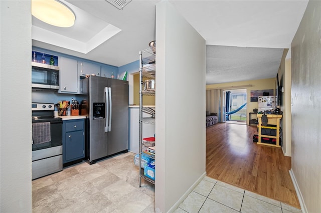 1100 E Bay Dr Unit 60, Largo, FL 33770 - kitchen with appliances with stainless steel finishes, blue cabinets, light tile patterned floors, and baseboards