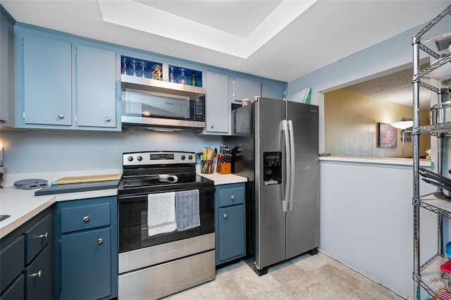 1100 E Bay Dr Unit 60, Largo, FL 33770 - kitchen with stainless steel appliances, light countertops, blue cabinetry, and a raised ceiling