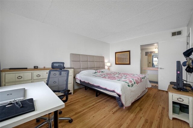 1100 E Bay Dr Unit 60, Largo, FL 33770 - bedroom featuring light wood finished floors, a textured ceiling, an office area, and ensuite bathroom
