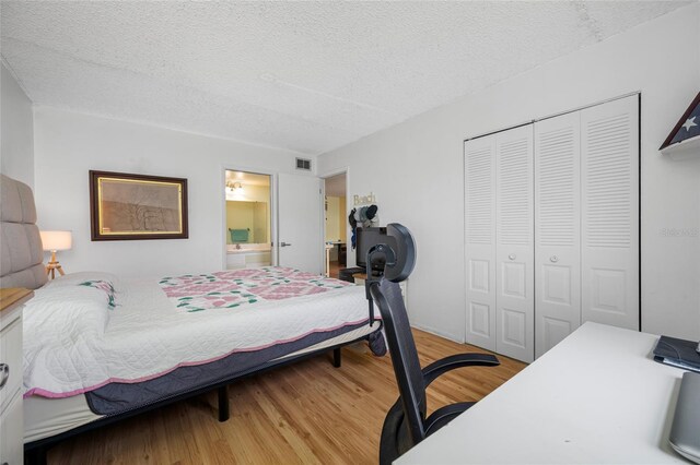 1100 E Bay Dr Unit 60, Largo, FL 33770 - bedroom featuring a closet, a textured ceiling, wood finished floors, and ensuite bath