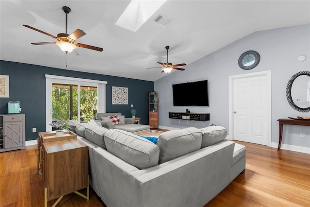 living room featuring a ceiling fan, vaulted ceiling, wood finished floors, a skylight, and baseboards