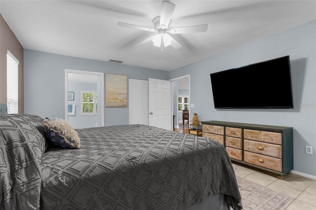 bedroom featuring multiple windows, light tile patterned flooring, ceiling fan, and baseboards