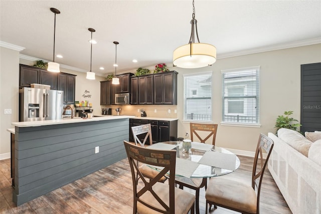 dining area with wood finished floors, baseboards, ornamental molding, and recessed lighting