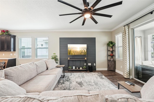 living area with wood finished floors, crown molding, ceiling fan, healthy amount of natural light, and baseboards
