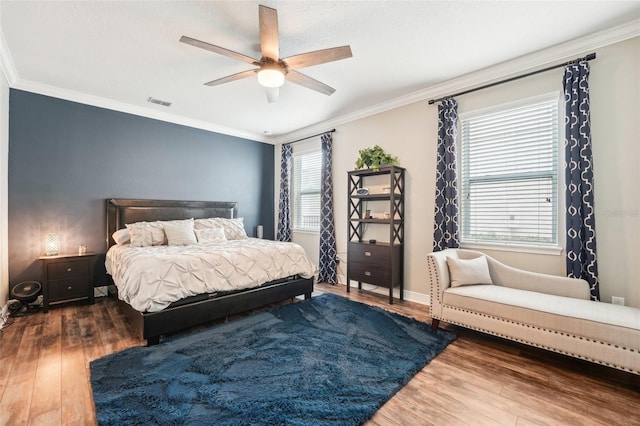 bedroom featuring wood finished floors, crown molding, multiple windows, ceiling fan, and baseboards