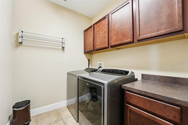 laundry area with cabinet space, washer and clothes dryer, baseboards, and light tile patterned floors