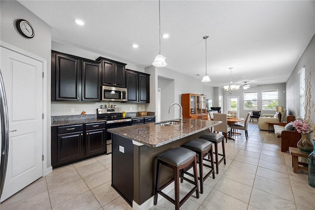 kitchen with appliances with stainless steel finishes, a sink, a kitchen breakfast bar, open floor plan, and light tile patterned floors
