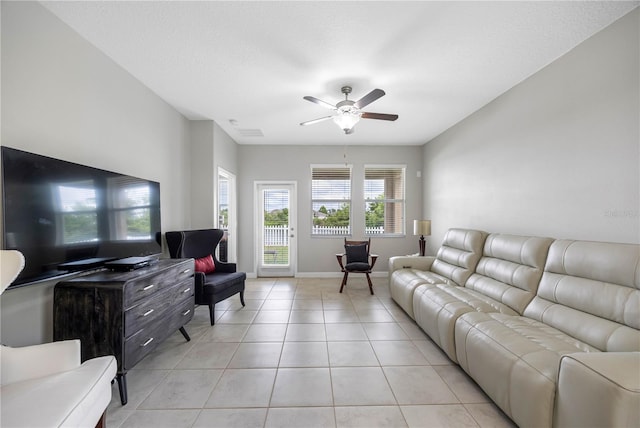 living area with light tile patterned floors, a ceiling fan, and baseboards