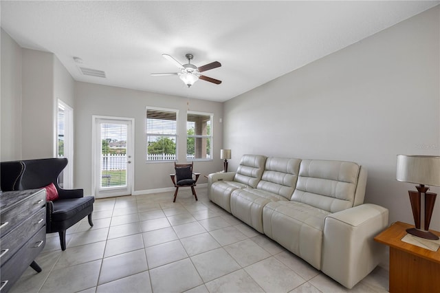 living area featuring a ceiling fan, light tile patterned floors, and baseboards